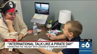 Teacher dressed as a pirate talking to student at desk